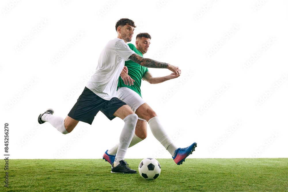 Competitive moment on soccer field as player in white blocks player in green's attempt to kick the ball against white background. Concept of professional sport, championship, final match, movement. Ad Competitive moment on soccer field as player in white blocks player in green's attempt to kick the ball against white background. Concept of professional sport, championship, final match, movement. Ad