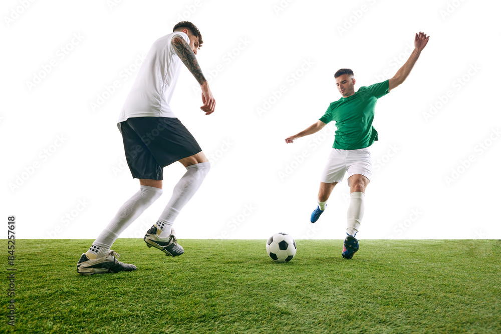 Obraz premium Player in white executes defensive move, challenging player in green's advance during soccer game on green lash playground against white background. Concept of sport, championship, match, movement. Ad