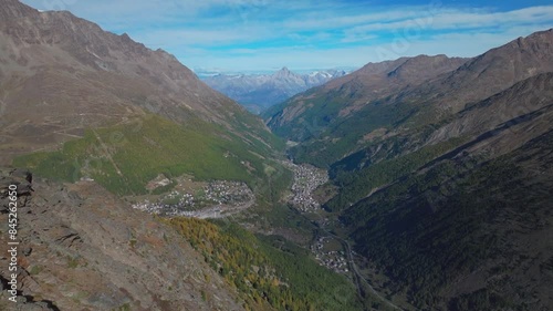 Visp Saas Fee Saastal aerial drone Switzerland beautiful sunny blue sky autumn fall yellow Larchs forest trees Swiss Alps alpine town in valley glacier glacial gondola tram chairlift forward reveal photo