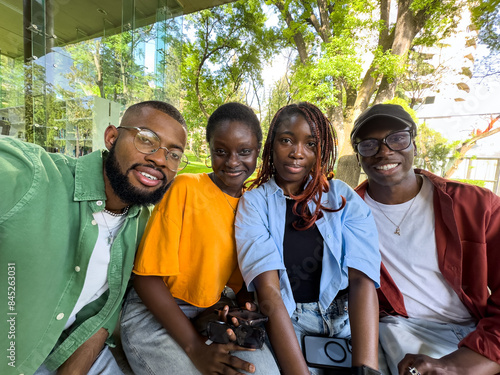 Four smiling African American college students take selfie outside university library take study break. Pleased black diversity friends looking at camera have fun together. photo