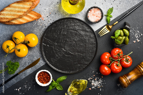 Black stone cooking background. Spices and vegetables. Top view. Free space for your text.