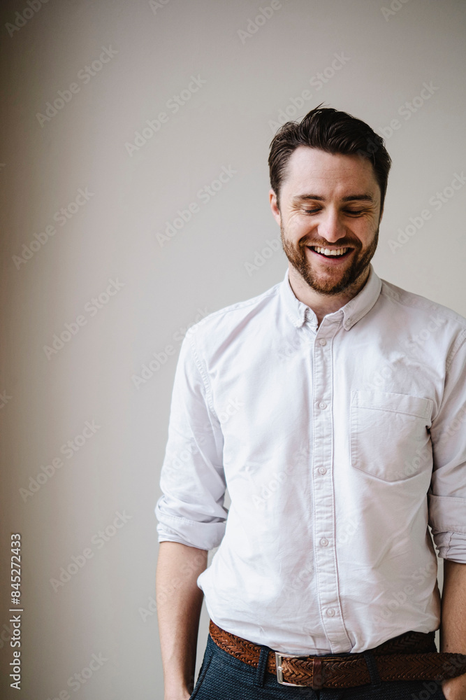 Happy businessman standing in front of wall Happy businessman standing in front of wall