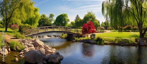 A picturesque park with a kids playground and a charming bridge over a shimmering creek captured in a sunny day panoramic image with plenty of empty space. Creative banner. Copyspace image photo