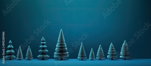 A blue background hosts four artificial Christmas trees in varying shades of blue and green The image includes copy space perfect for a Christmas concept or card