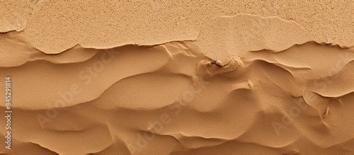 A closeup top view of a natural sandy beach with a brown dry sand texture perfect for summer designs The sand or soil on the beach creates a wavy and textured background image. Creative banner photo