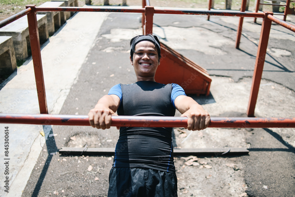 Obraz premium Excited Young Asian Male Fitness In Sporty Holding Pulling Up Gymnastic Rings Lifting Working Out In Gym Outdoor.