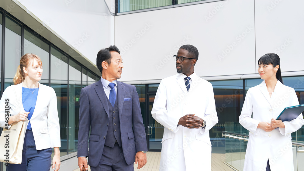 A group of multinational business people and engineers in white coats walking and talking A group of multinational business people and engineers in white coats walking and talking