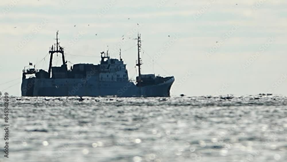 Big fishing boat trawling and catching fish as it crosses sea at horizon line during sunset. the fishing and sea-faring industry. Slow motion. Vessel crossing sea at horizon line. Big fishing boat trawling and catching fish as it crosses sea at horizon line during sunset. the fishing and sea-faring industry. Slow motion. Vessel crossing sea at horizon line.