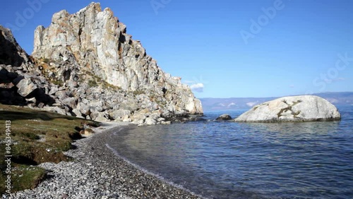 Video of Baikal Lake in sunny morning on Olkhon Island. Clear water on pebble beach near famous Shamanka Rock or Cape Burkhan. Travel, active recreation and outdoors photo