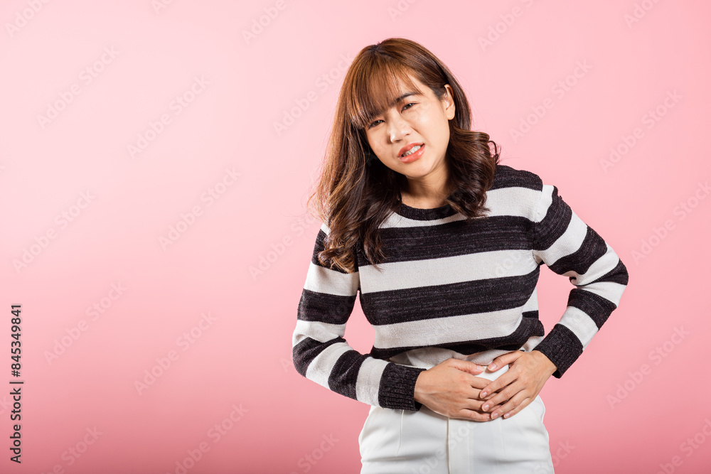 Portrait of Asian beautiful young woman has stomachache, female abdominal pain suffering from stomach ache, studio shot isolated on pink background, period pain, Health and medical gastritis concept Portrait of Asian beautiful young woman has stomachache, female abdominal pain suffering from stomach ache, studio shot isolated on pink background, period pain, Health and medical gastritis concept