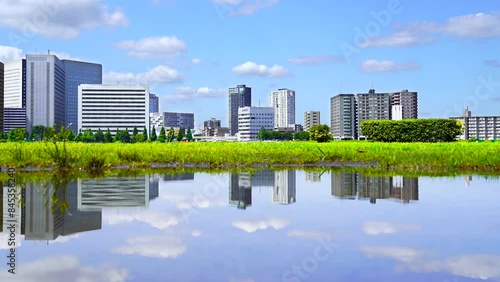 【神奈川県・川崎市】川崎の都市風景　雨上がりの多摩川河川敷　水面に映る街並み　4K映像　パンレフト　
The Tama River after the rain. The cityscape of Kawasaki reflected in a puddle - Kanagawa, Japan - 4K video - pan left photo