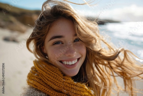 Young woman wearing a scarf smiling with the sea in the background