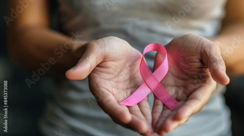 Template design with a close-up of a teenage hand holding a pink ribbon for breast cancer awareness month