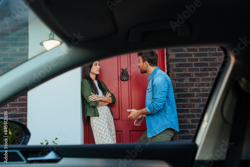 Couple conversing by a car and red door