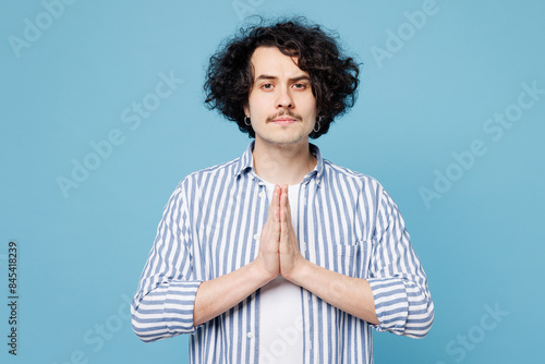 Young man wear shirt white t-shirt casual clothes hold hands folded in prayer gesture, begging about something isolated on plain pastel light blue cyan background studio portrait. Lifestyle concept. photo