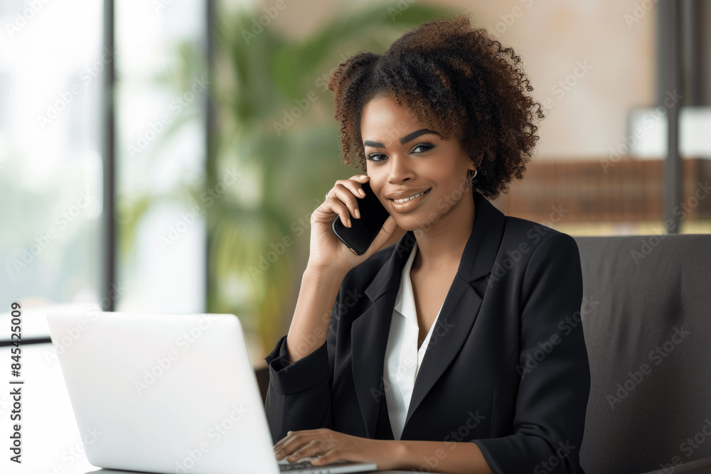 African American Businesswoman Using Laptop and Mobile Phone in Office