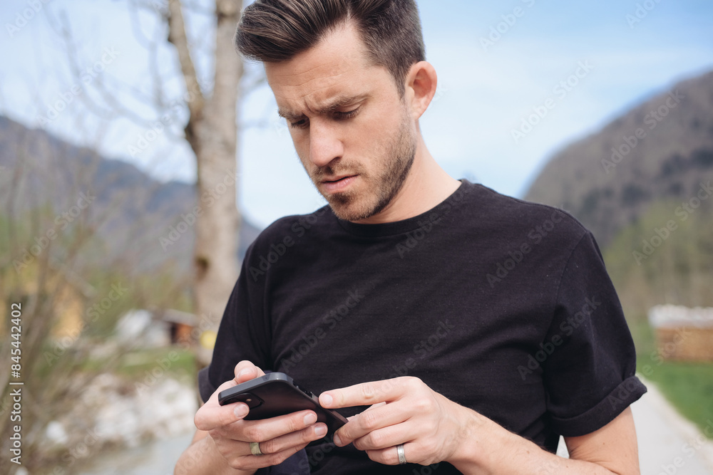 A young man looking at his smartphone, in a village A young man looking at his smartphone, in a village