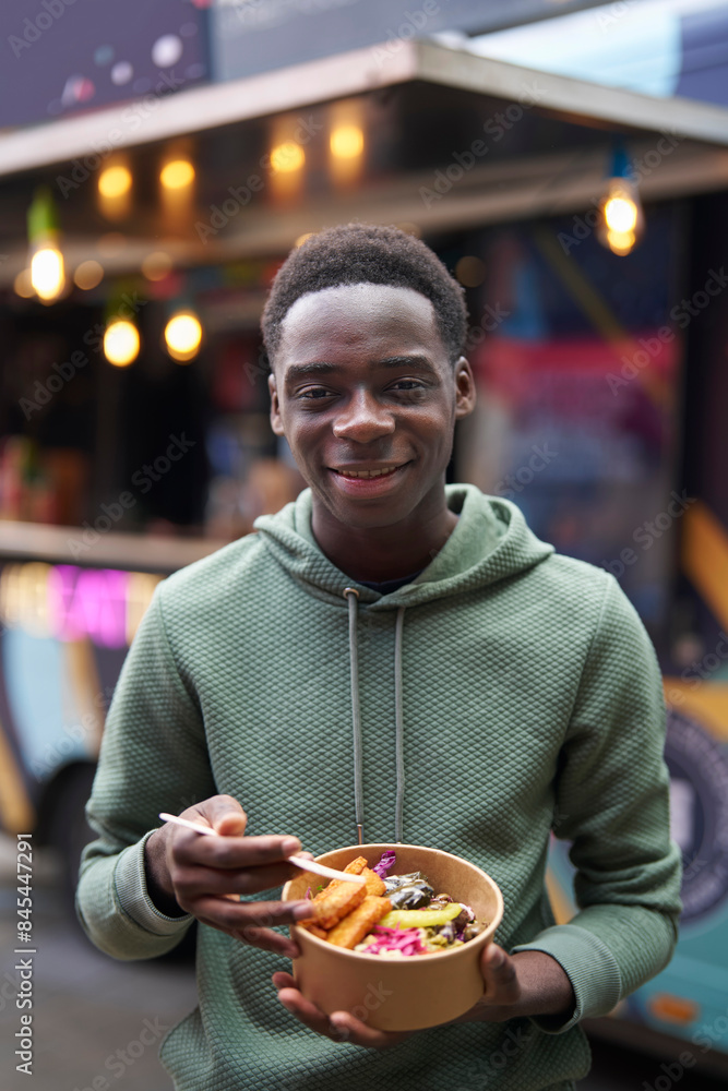 Portrait Of Teenage Boy Eating Vegan Mezze Bowl At Outdoor Street Food Market Portrait Of Teenage Boy Eating Vegan Mezze Bowl At Outdoor Street Food Market