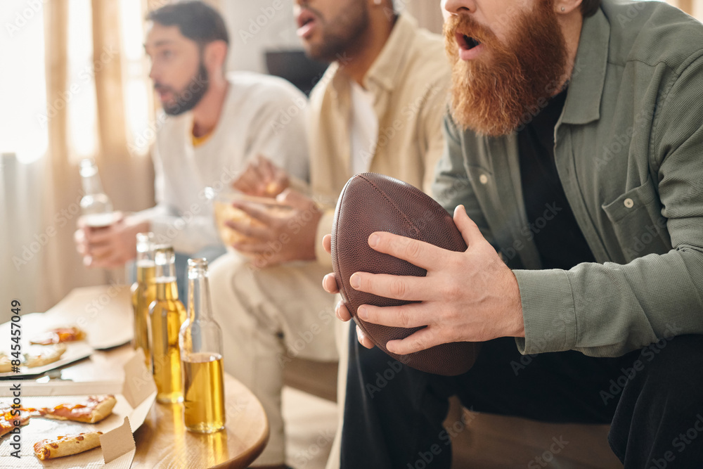 Three cheerful, interracial men in casual attire sit around a table, engrossed in a football game. Three cheerful, interracial men in casual attire sit around a table, engrossed in a football game.