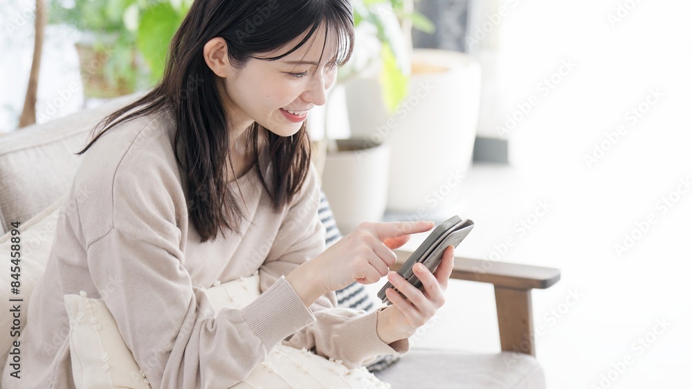 リビングでスマホを見る女性 リビングでスマホを見る女性