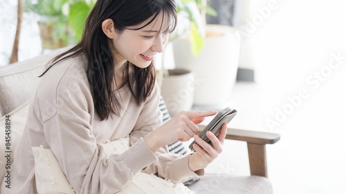 リビングでスマホを見る女性