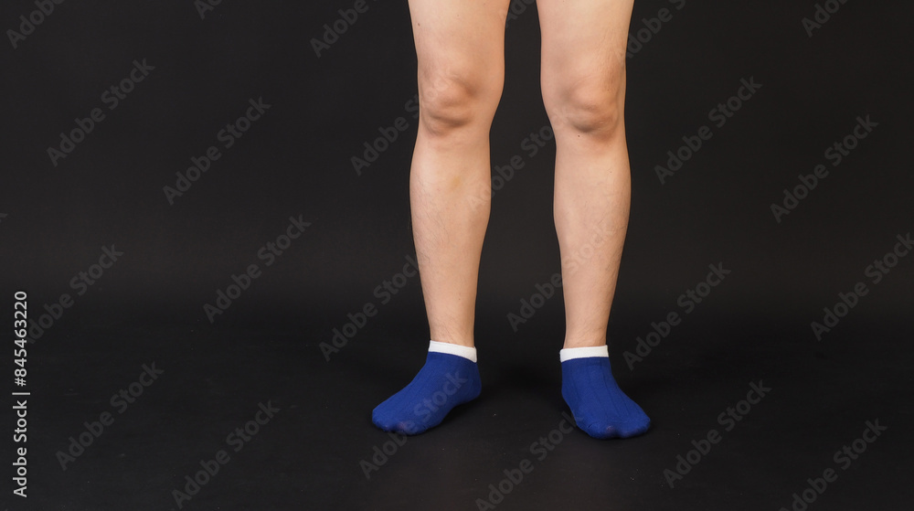 Male legs wear blue sock is isolated on black background. Male legs wear blue sock is isolated on black background.