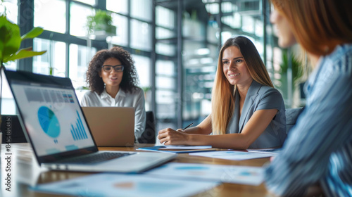 Businesswomen discussing at a meeting table in a modern office with a laptop