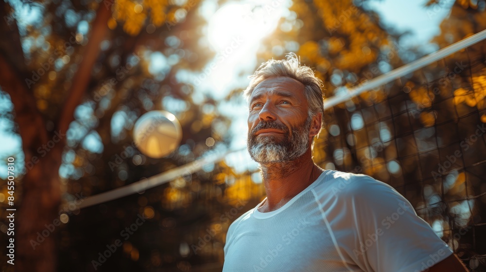 Mature Man Playing Volleyball with Family and Friends Outdoors on a Sunny Day Mature Man Playing Volleyball with Family and Friends Outdoors on a Sunny Day