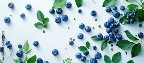 Fresh ripe blueberries and leaves grouped together against a white backdrop. photo