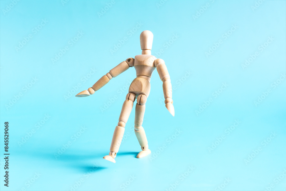The concept of an indecisive person who takes a step forward. A wooden doll takes a step forward against a bright background. The concept of an indecisive person who takes a step forward. A wooden doll takes a step forward against a bright background.