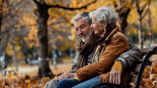 Senior Couple Embracing Tender Moment on Park Bench Amid Serene Autumn Afternoon © spyrakot