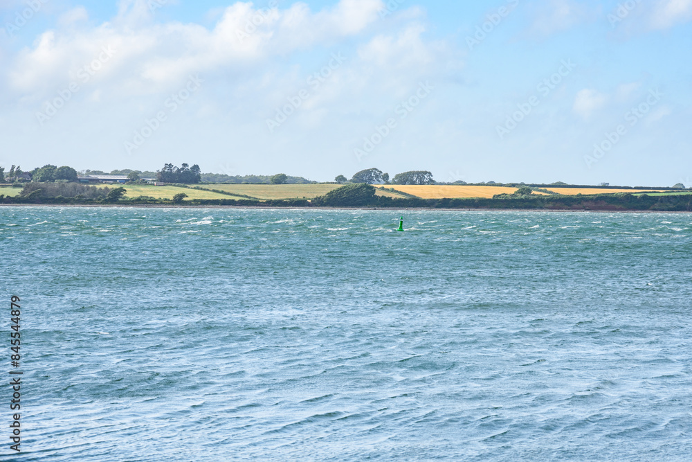 Obraz premium Agricultural fields along a windy coast on a clear summer day