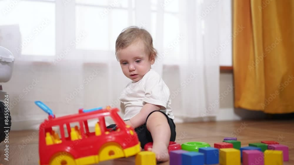 a small child is playing. happy childhood dream concept for a little child. cute little child in a white t-shirt plays with different colorful toys while sitting lifestyle on the floor a small child is playing. happy childhood dream concept for a little child. cute little child in a white t-shirt plays with different colorful toys while sitting lifestyle on the floor