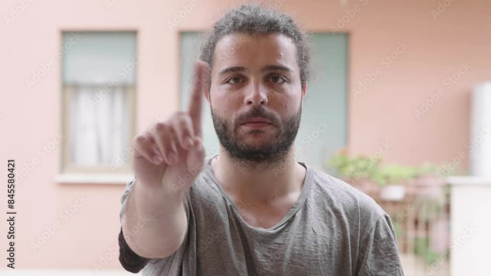Man in 30s with long hair shaking finger on terrace Man in 30s with long hair shaking finger on terrace