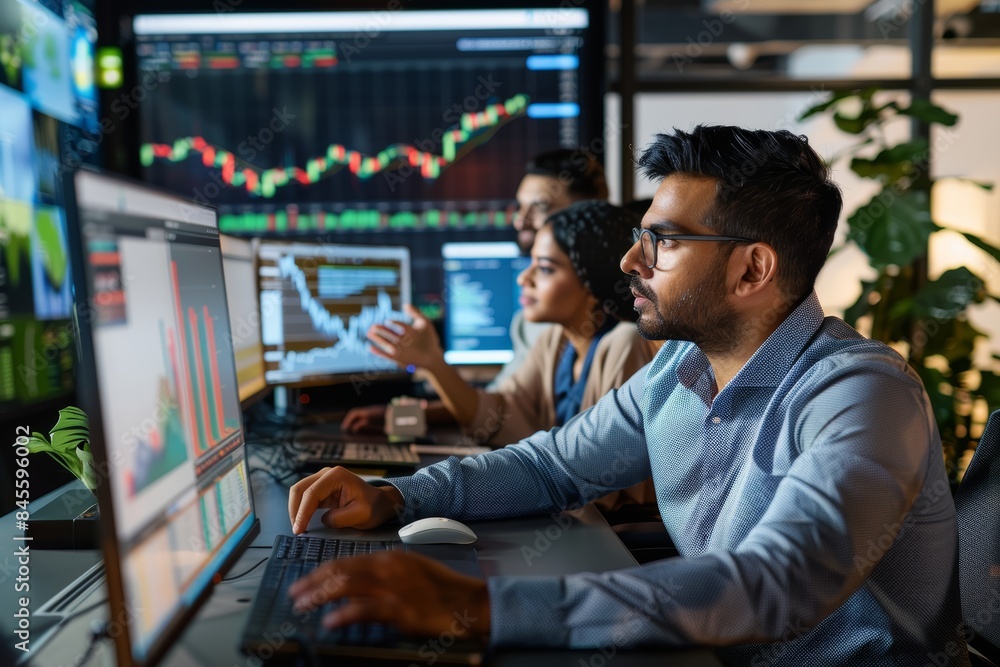 © spyrakot - Financial Analysts Collaborating on Investment Strategies with Data Charts in Modern Office