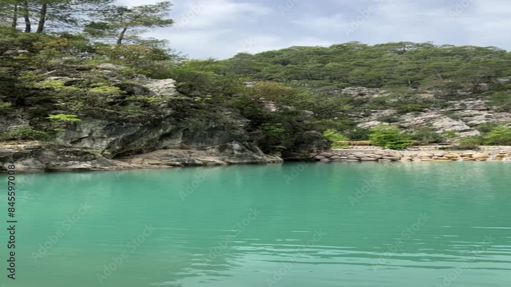 View of a mountain lake with blue water. Vertical video of a mountain lake among rocks and trees