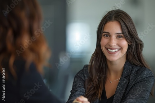 A close-up of a smiling businesswoman shaking hands with a man after signing a contract in an office.
