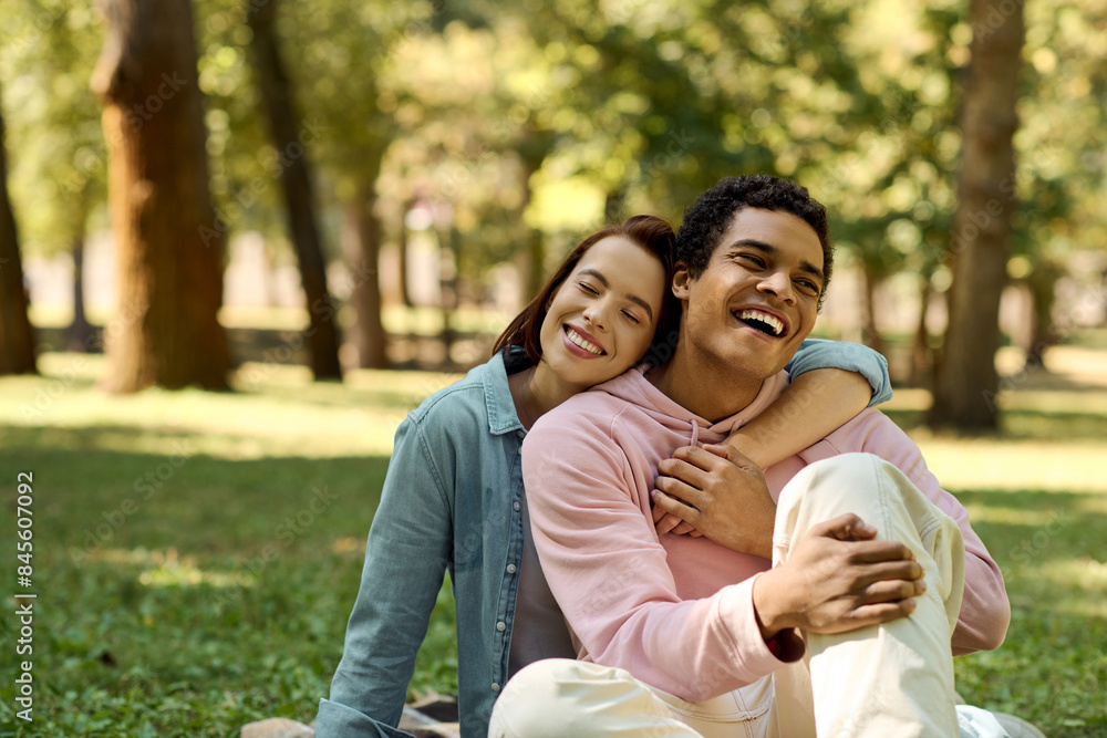 A man and a woman are sitting on the grass in a park, dressed in vibrant attires, embracing each other in a moment of serenity. A man and a woman are sitting on the grass in a park, dressed in vibrant attires, embracing each other in a moment of serenity.