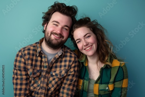 Portrait of a jovial couple in their 30s dressed in a relaxed flannel shirt over soft teal background © Markus Schröder