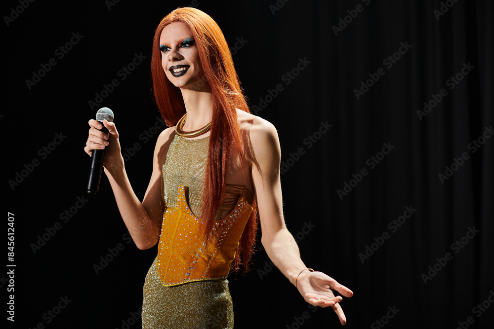 A drag queen in a shimmering gold dress holds a microphone on stage. A drag queen in a shimmering gold dress holds a microphone on stage.