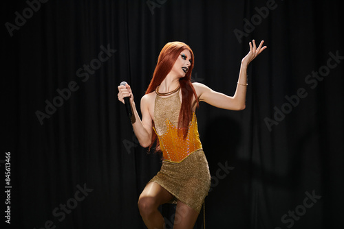 Vászonkép A drag queen in a sparkling gold dress performs on stage.