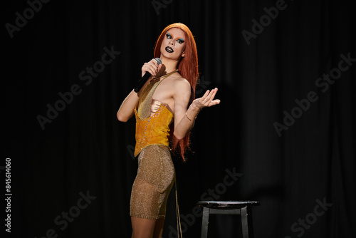 фотографія A drag performer in a shimmering gold dress takes the stage, microphone in hand