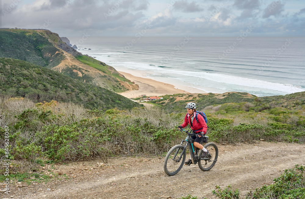 happy active senior woman cycling on the the rocky cliffs of the Vicentina coast of Algarve, Portugal near Sagres and Vila do Bispo happy active senior woman cycling on the the rocky cliffs of the Vicentina coast of Algarve, Portugal near Sagres and Vila do Bispo