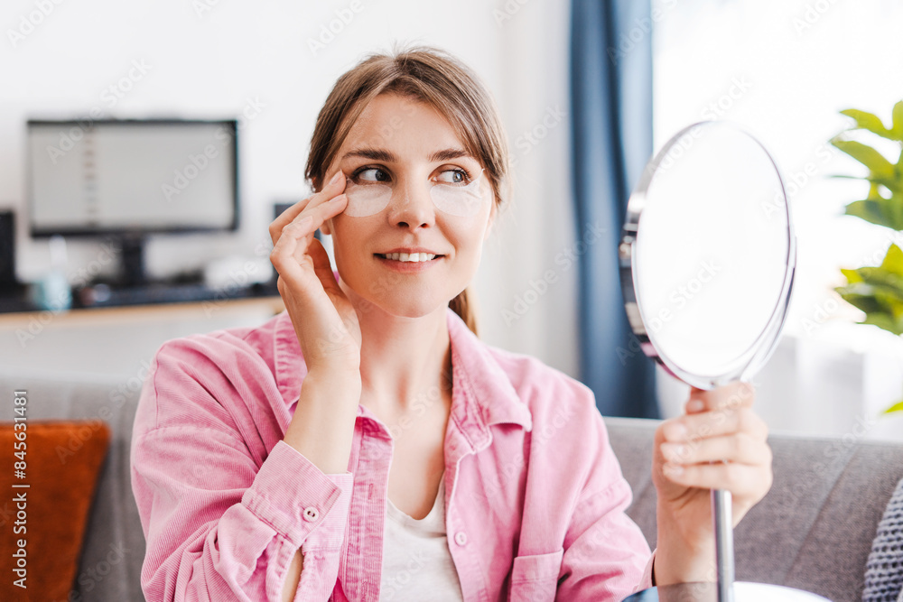 Cute, beautiful woman with patches under her eyes on her face, holding mirror, looking into it Cute, beautiful woman with patches under her eyes on her face, holding mirror, looking into it