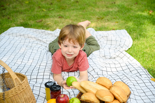 Happy children lying down on picnic fabric with food for picnic in nature on a summer day. little boy genuine emotions..