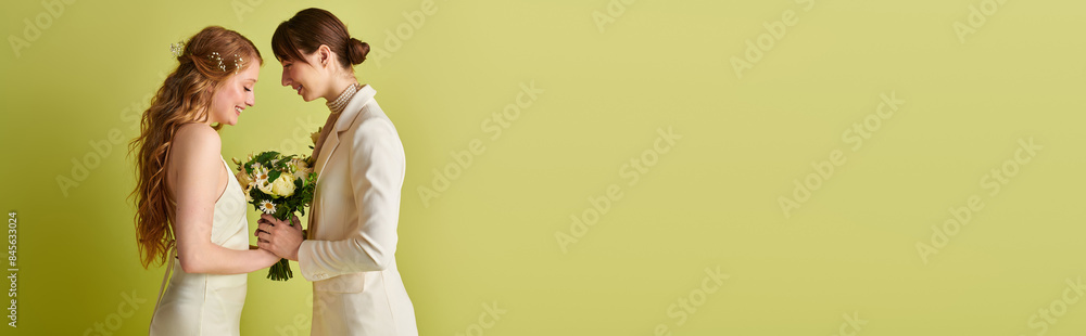 Two brides in white wedding attire stand against a green background, holding a bouquet of flowers. Two brides in white wedding attire stand against a green background, holding a bouquet of flowers.