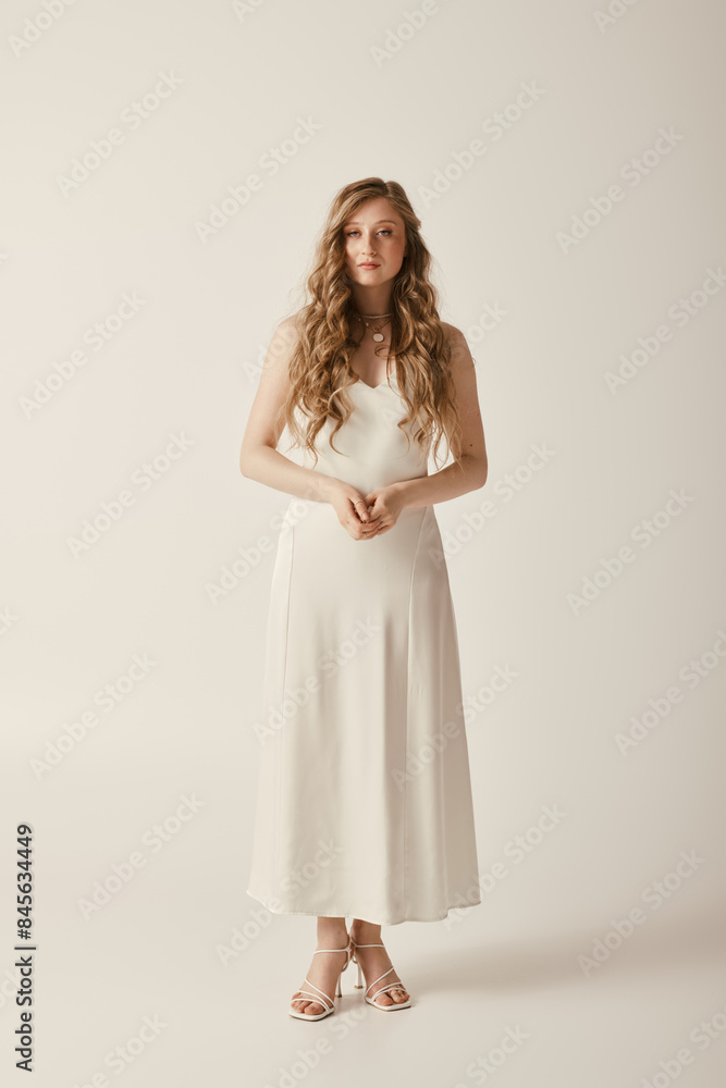 A beautiful young bride stands in a simple white wedding dress on a white background. A beautiful young bride stands in a simple white wedding dress on a white background.
