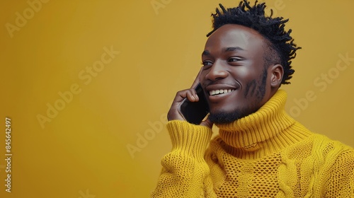 Smiling Man Talking on Phone in Yellow Sweater Against Yellow Background