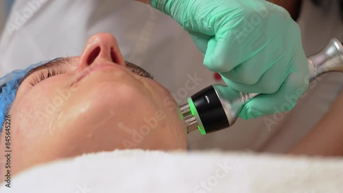 Facial skin care, close up. Woman undergoes ultrasound cavitation facelift procedure. Anti aging facial rejuvenation. Ultrasound face lifting in cosmetology photo