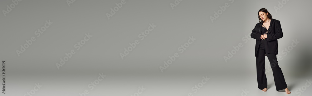 A beautiful plus-size woman strikes a pose in stylish attire against a gray backdrop. A beautiful plus-size woman strikes a pose in stylish attire against a gray backdrop.